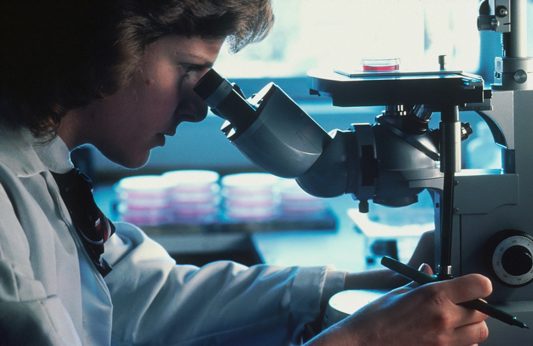 Женщина-ученый смотрит в микроскоп