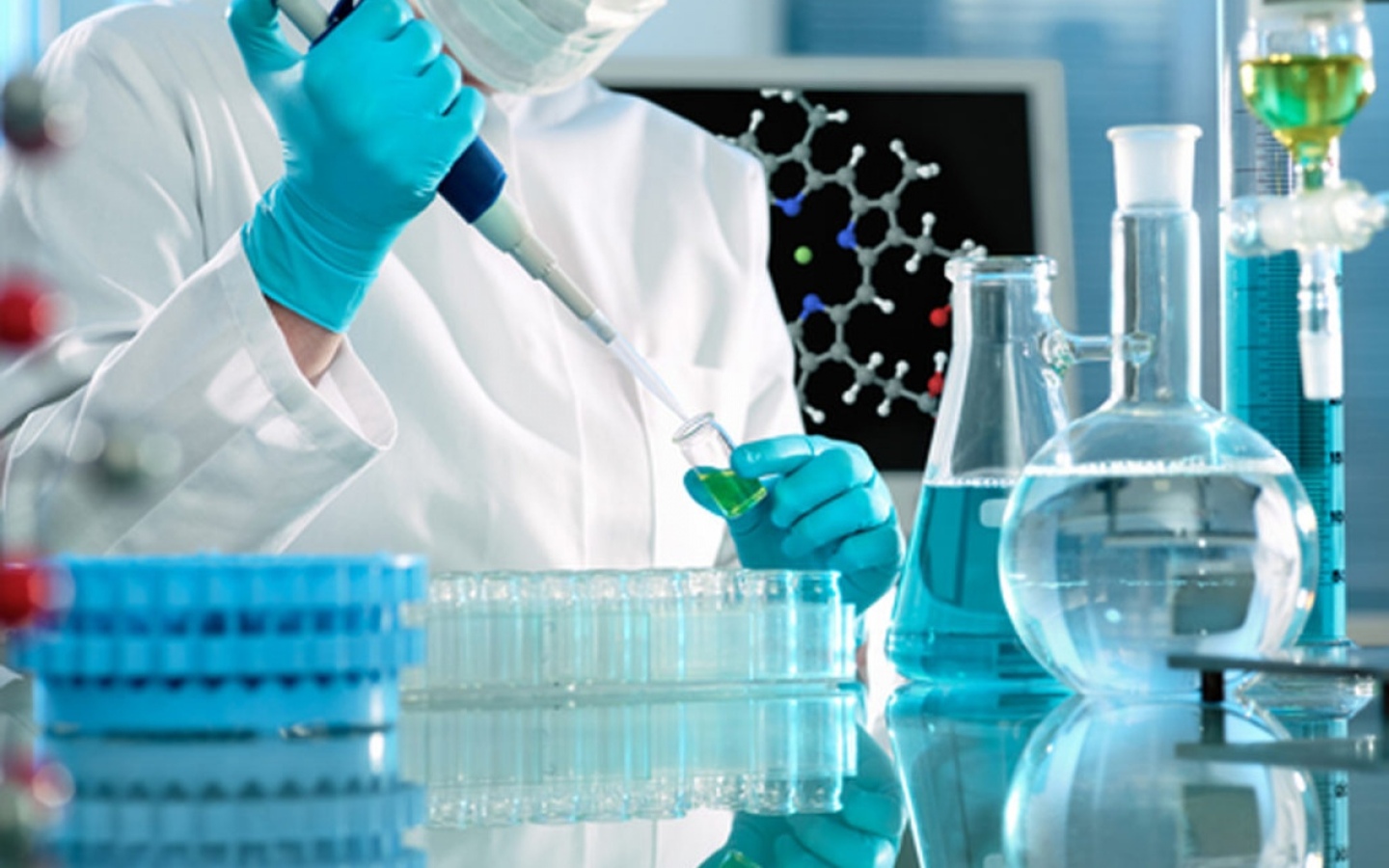 Рука лаборанта в белом халате и медицинской синей перчатке держит пробирку и стеклянную палочку